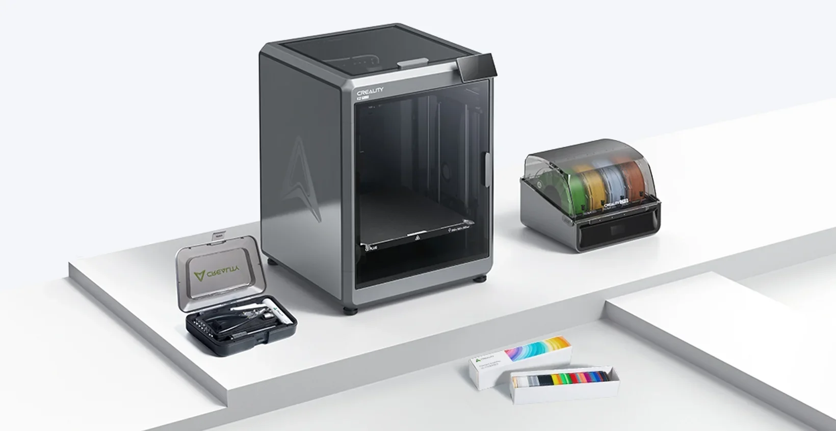 Creality K2 3D printer with toolkit, filament spools, and materials on a white display stand, featuring branding and accessories.