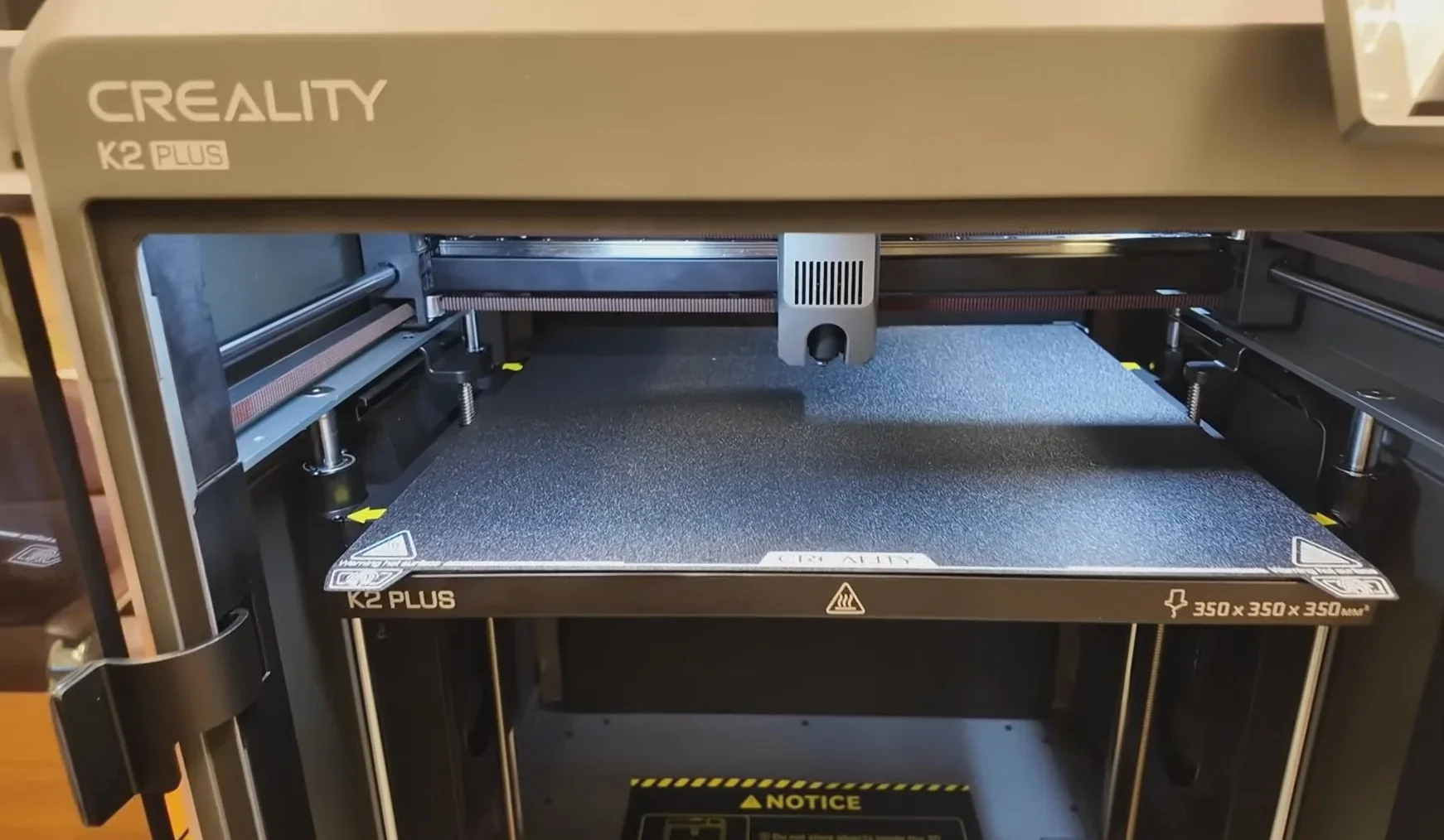 Creality K2 Plus 3D printer interior with a textured build plate, visible branding, and a working area labeled 350x350x350 mm.