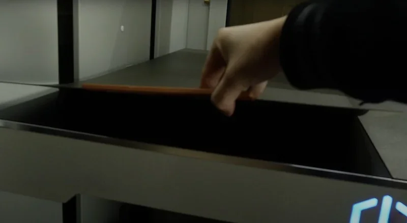 Hand opening the door of a Creatbot D1000 3D printer, revealing a spacious printing chamber in an industrial setting.