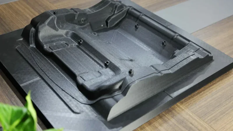 creatbot d1000 printed industrial part, black, detailed design on a wooden surface, emphasizing precision and scale of 3D printing technology.