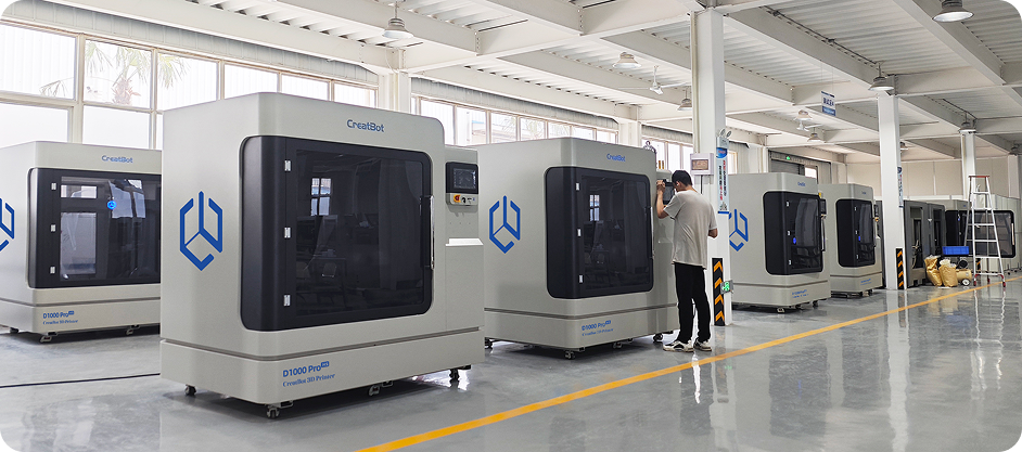 Creatbot D1000 Pro HS 3D printers lined in a spacious industrial setting. A person operates one, surrounded by samples presumably made by the printer.