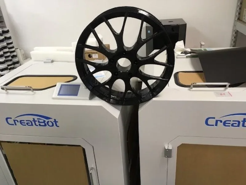 CreatBot D600 Pro in a workshop, featuring a large black 3D-printed wheel on top, showcasing the printer's capability.