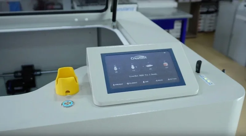 CreatBot D600 Pro2 3D printer control panel with touchscreen interface, yellow tool holder, in a workshop environment.
