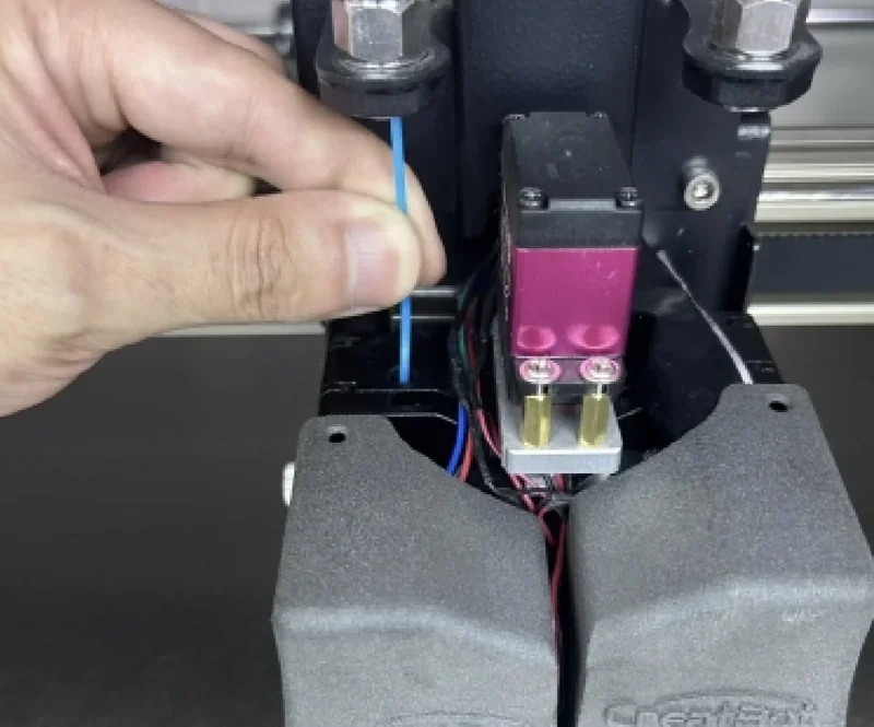 Loading filament into Creatbot D600 Pro2 HS 3D printer extruder, showing hands, wiring, and branding details.