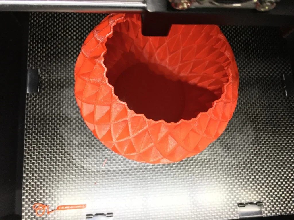 Creatbot F160 3D printer creating an orange, geometric-patterned vase on a textured print bed.