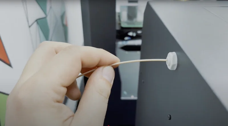 A hand loads filament into the Creatbot F160 3D printer, highlighting its feeding mechanism.