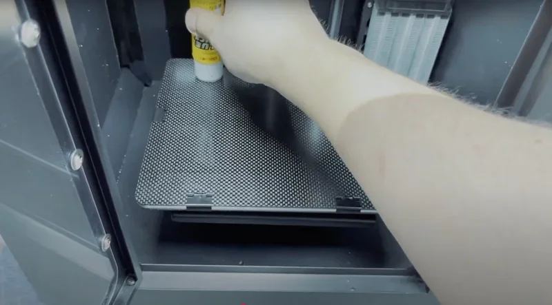 Creatbot F160 3D printer interior with hand applying glue stick on print bed, showcasing preparation for printing.