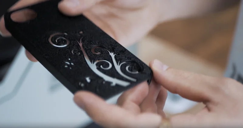 Hands holding an intricately patterned black 3D-printed cover, created by the Creatbot F430 printer, showcasing precision and detail.