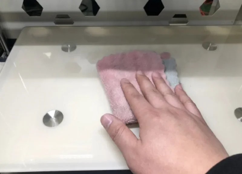 Hand cleaning a Creatbot F430 3D printer's bed with a cloth, showing maintenance of commercial 3D printers.