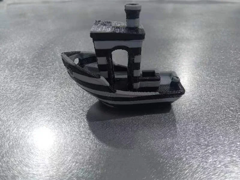 3D-printed black and white striped boat model created by Creatbot F430 NX on a reflective silver surface.