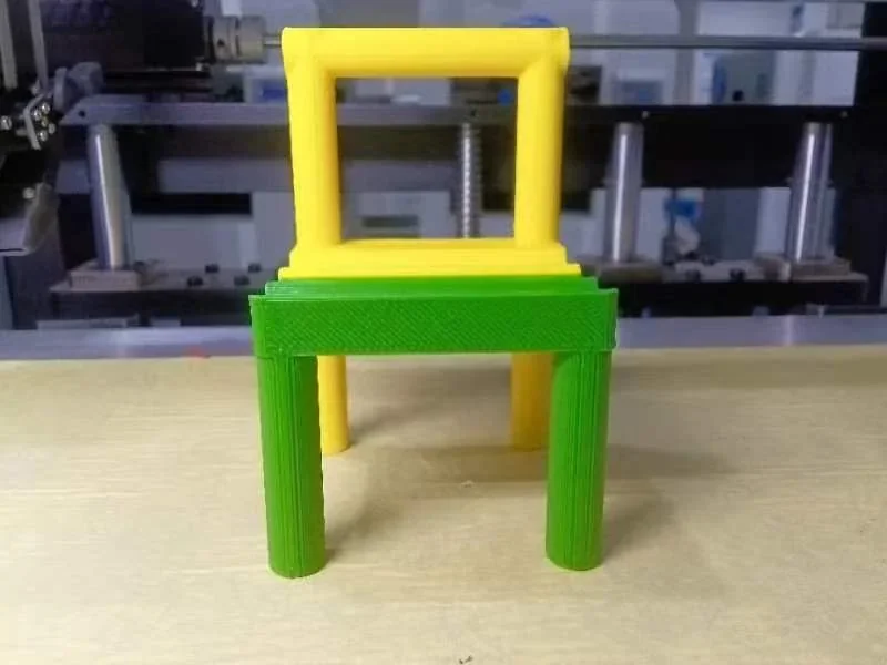 CreatBot F430 NX 3D-printed stacked yellow and green chairs in a workshop setting.