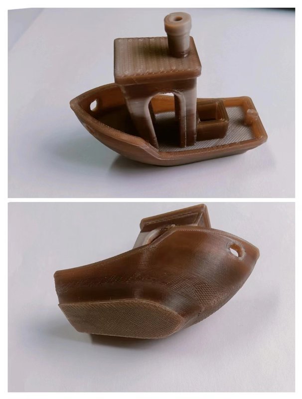 A side and under view of a small brown 3D printed boat figurine created by the CreatBot PEEK-250. The boat features a detailed cabin with a chimney, smooth hull, and distinct layers visible on the surface, indicating the high level of precision and capability of the printer. The object is placed on a plain white background providing a clear view of the intricate details achieved by the 3D printer.