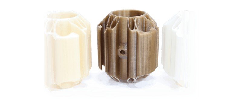 A set of three cylindrical parts printed by the CreatBot PEEK-250 displayed vertically. The central object is a brown cylindrical component with intricate vertical grooves showing precise engineering design, while the flanking parts are similar in design but in a lighter color. The high-resolution print quality demonstrates the printer's ability to handle complex geometries and high-performance materials like PEEK, PA, and other engineering plastics. These parts are likely used for industrial applications where durability and precision are critical.