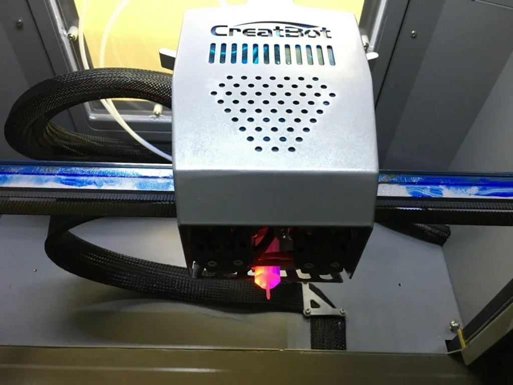 Creatbot PEEK-300 3D printer interior showing the active nozzle and structured cabling in an industrial setup.