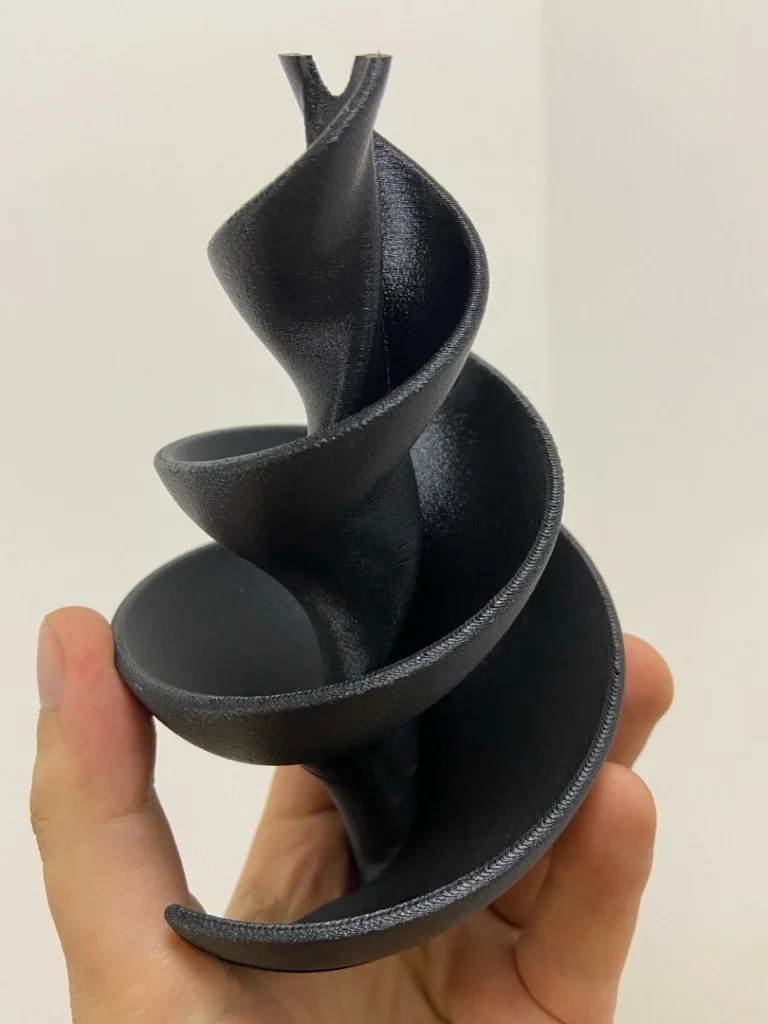 Hand holding a black spiral object 3D printed by creatbot peek-300, showcasing smooth finish and precise design.