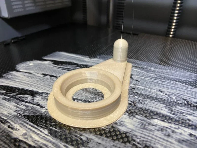 3D printed part on textured bed, created by Creatbot PEEK-300, showcasing intricate detailing and circular design in a professional setting.