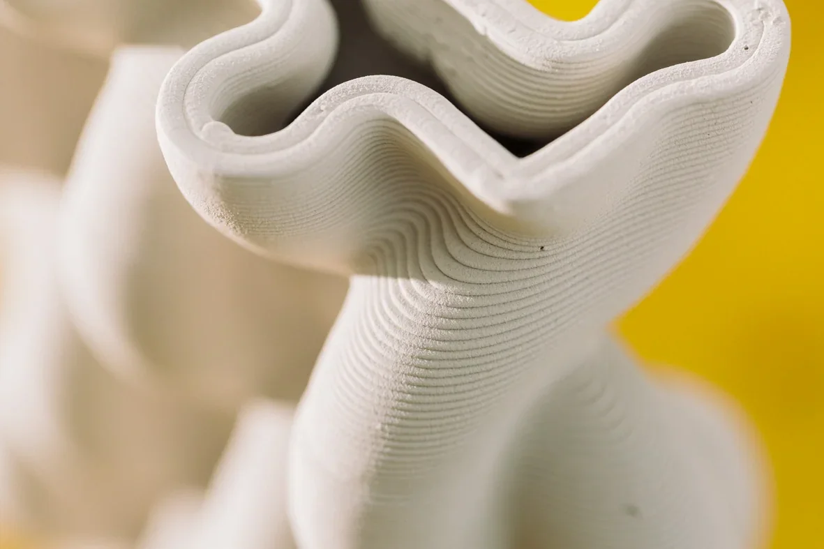 Wavy clay object with smooth layers, created by Delta WASP 2040 Clay, set against a bright yellow background.