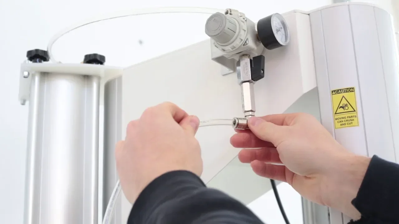 Hands adjusting the Delta Wasp 2040 Clay 3D printer component, visible pressure gauge and caution label, in a bright setting.