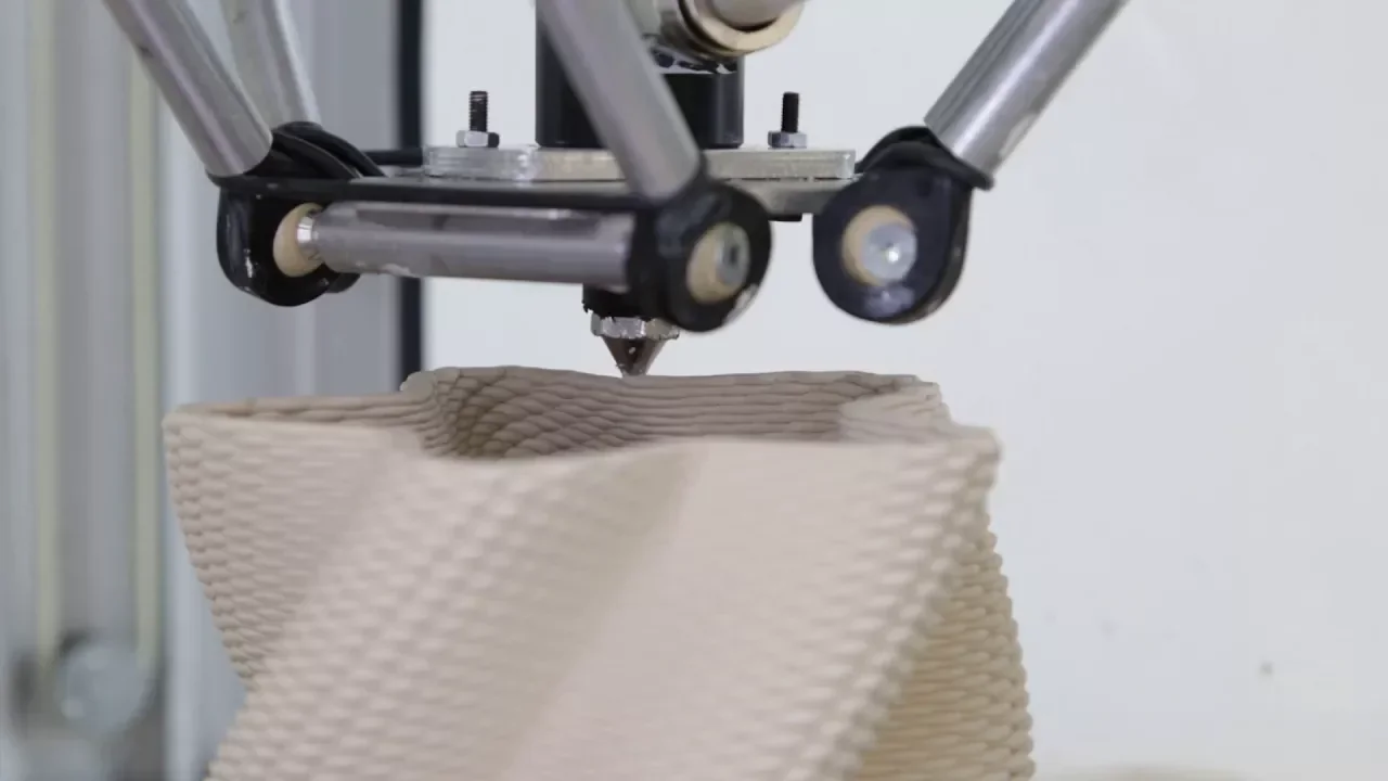 Delta WASP 2040 Clay 3D printer creating a detailed ceramic structure, showcasing the precision of its extruder and metallic arms.