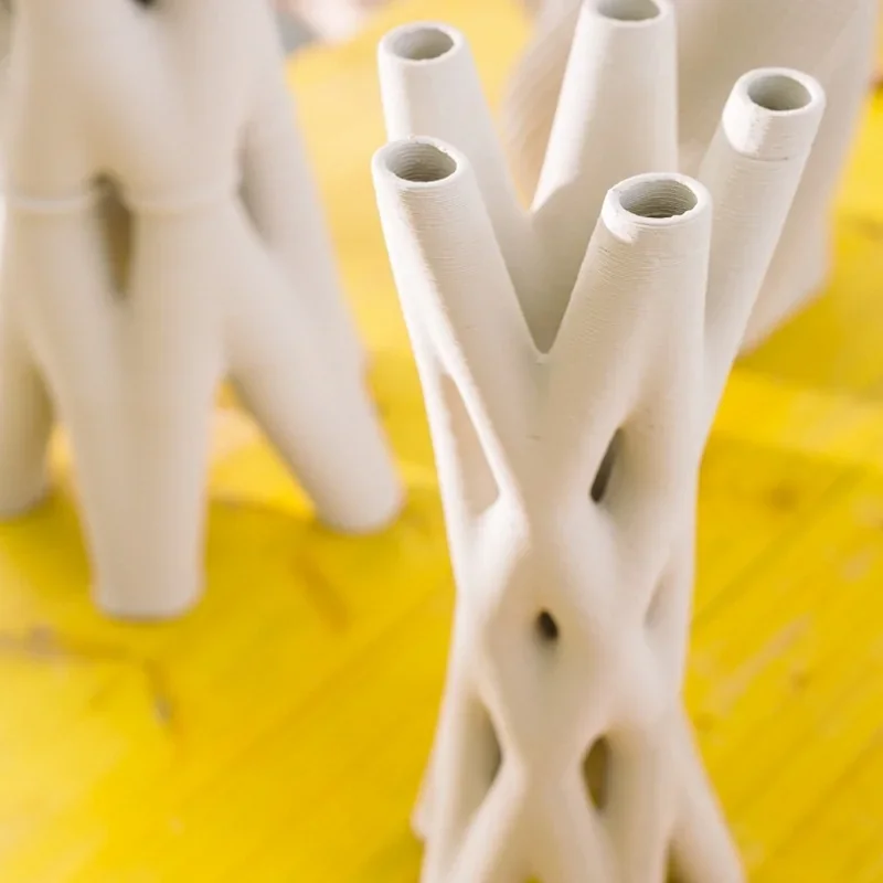 3D-printed clay structures with tubular design on a yellow surface, created by Delta WASP 2040 Clay printer.