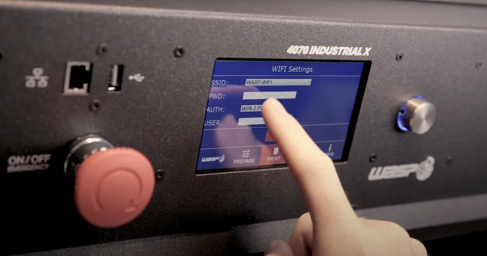 Delta WASP 4070 Industrial X displaying WiFi settings on touchscreen, with emergency button and controls visible. Branding displayed.