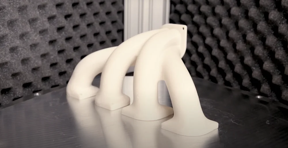 3D-printed cream-colored manifold created by Delta WASP 2040 Industrial X on a reflective surface with foam-padded walls in the background.