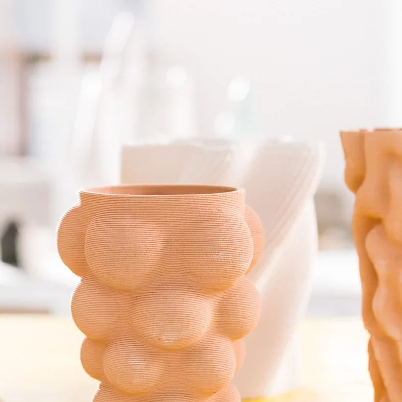 3D printed ceramic vases with bulbous texture created by delta wasp 2040 pro, displayed in a bright room.