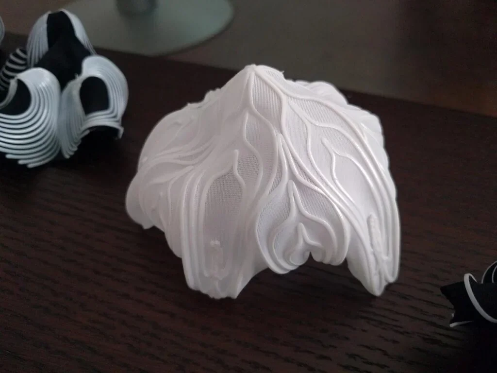3D-printed white organic shape on a table, created by Delta Wasp 2040 Pro, showcasing intricate swirling details and design complexity.