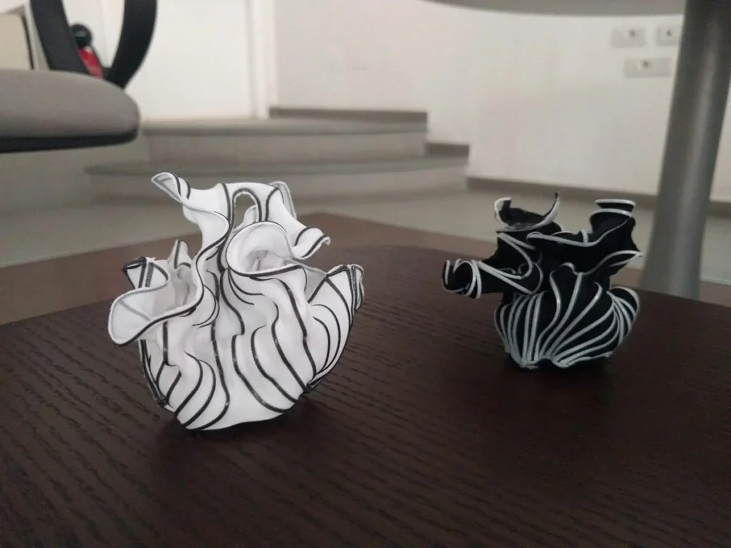 Intricate black and white 3D printed sculptures on a table, crafted using the delta wasp 2040 pro, in a modern interior setting.