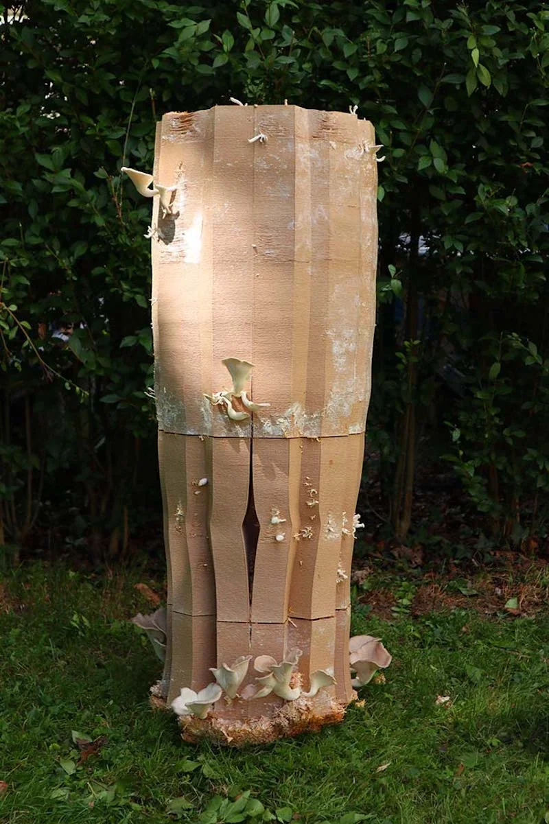 3D-printed totem-shaped object with mushroom growth, created by Delta Wasp 3MT, standing on grass with a leafy background.