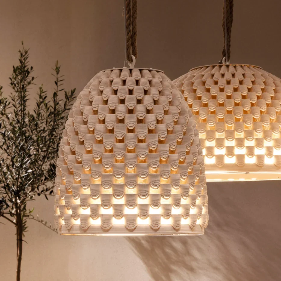 3D-printed clay light shades with intricate patterns, crafted by delta wasp 40100 clay, hanging indoors, emitting warm light.