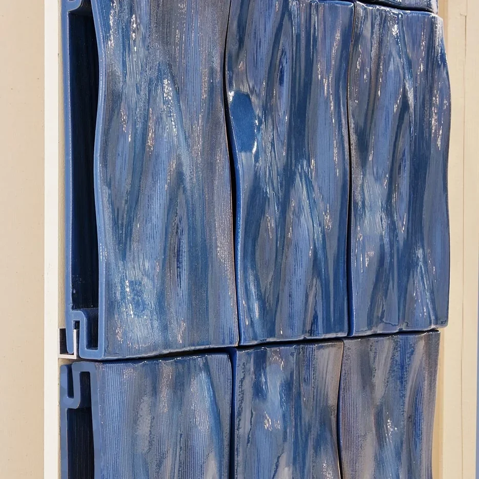 Blue clay tiles with glossy, wavy textures created by Delta WASP 40100 Clay, arranged in a grid on a vertical surface.