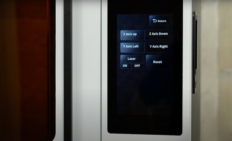 The image features a section of the Emake3D Galaxy 1 3D printer. The printer's interface includes a sleek, modern touch screen panel with options for manual control of the 3D printer's axes. Visible buttons on the screen are labeled “Z Axis Up,
