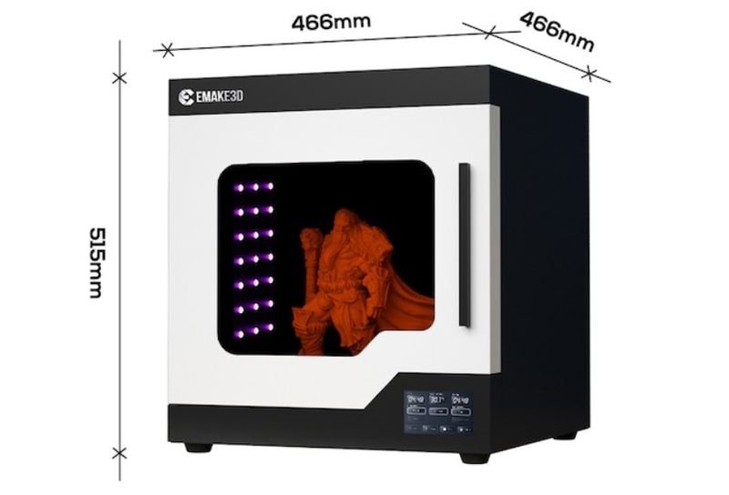 The emake3D Galaxy 1 3D printer is depicted as a sleek, modern appliance with a cubic shape. Its dimensions are prominently displayed as 466mm in width and depth, and 515mm in height. The printer features a front panel with a viewing window revealing an intricately detailed orange figure, showcasing its printing capability. The design includes a side-opening door with a vertical handle and a control panel located at the lower front right corner displaying various buttons and indicators. The emake3D branding is visible on the top left, enhancing brand recognition. The black and white color scheme gives it a contemporary aesthetic suitable for professional or personal use.