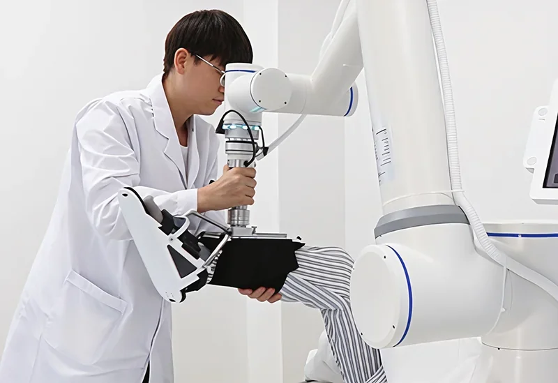Technician operates fairino fr16 robotic arm on patient's leg in a clinical setting, showcasing precise medical application.