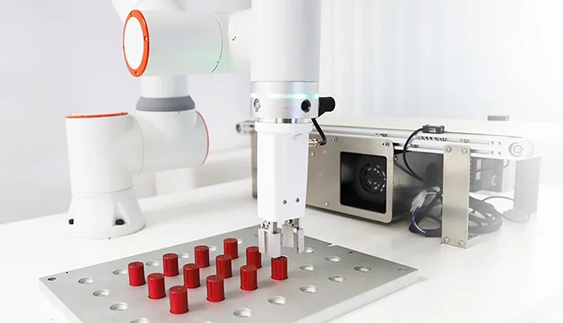 Fairino FR3 robotic arm arranges red cylindrical parts on a grid with precision; industrial setting, sleek design, and visible machinery present.