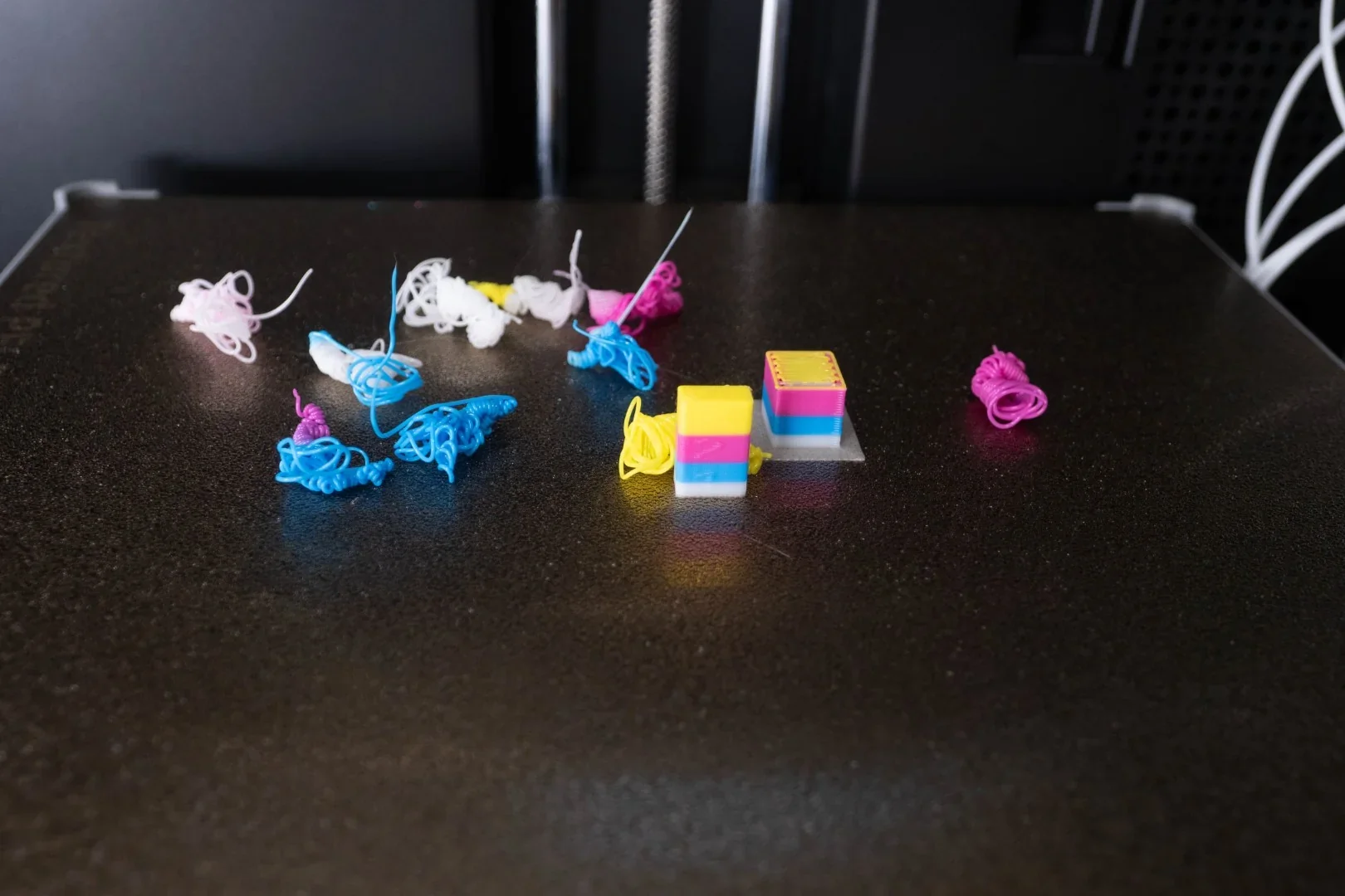 Flashforge AD5X 3D printer with colorful filament scraps and two multicolored cube samples on print bed.