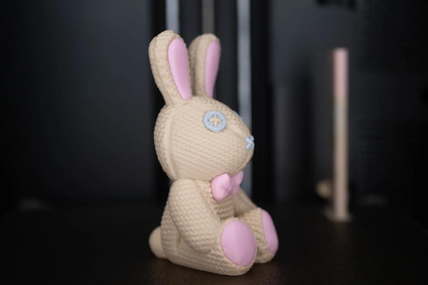 Beige and pink bunny toy with button eyes and bow tie, 3D printed by Flashforge AD5X, set against a dark background.