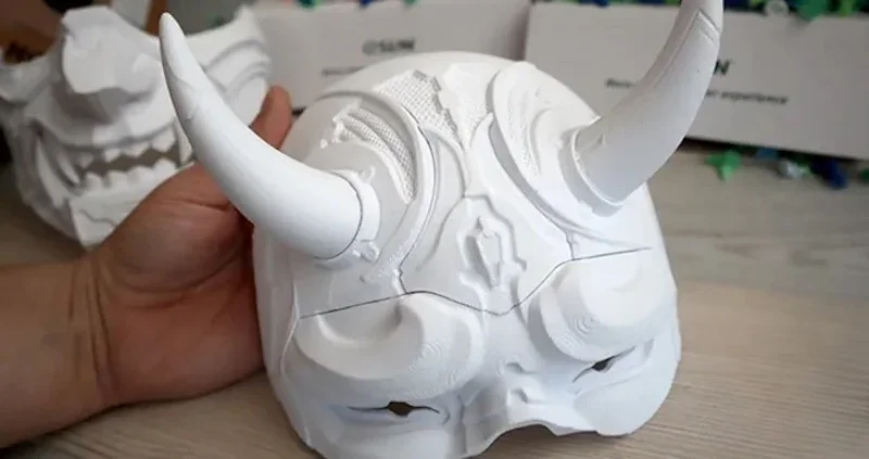 Flashforge AD5X 3D printed white horned mask held in hand, showcasing intricate details and craftsmanship.