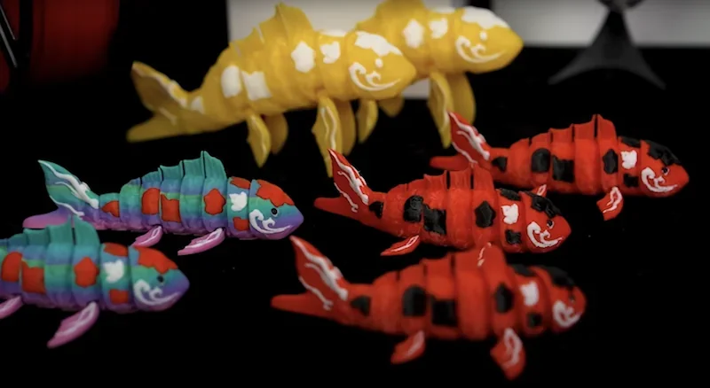 Colorful 3D printed koi fish showcasing intricate details, produced by Flashforge ad5x, against a black background, highlighting precision and craftsmanship.