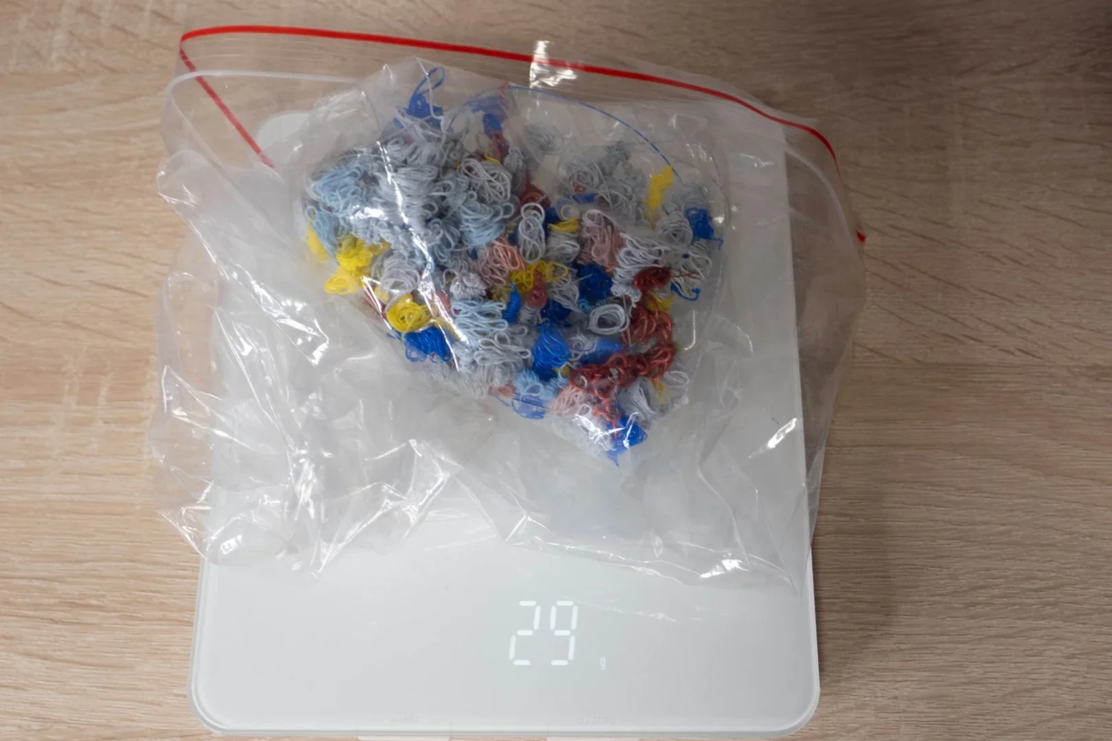 Bag of colorful shredded plastic weighing 29g on a digital scale from Flashforge AD5X 3D printer.