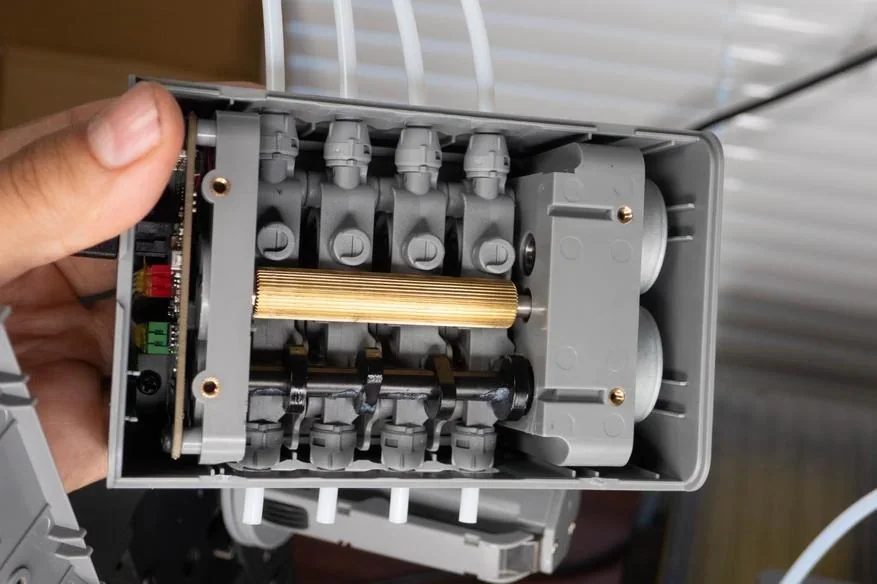 Flashforge AD5X 3D-printed engine model held by hand, showcasing intricate gray components and gears, highlighting printing detail and precision.