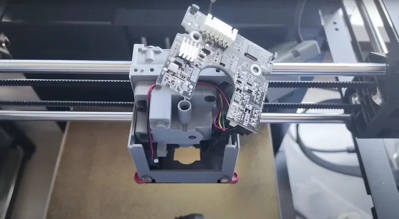Flashforge Adventurer 5M printer component with circuit board, wires on print head assembly, showcasing technical inner workings and structure.