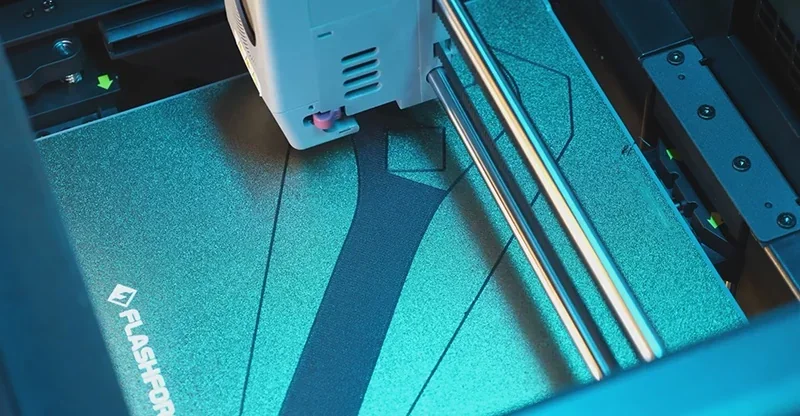 Flashforge Adventurer 5M Pro printing on a textured build plate, showing intricate print design and visible branding.