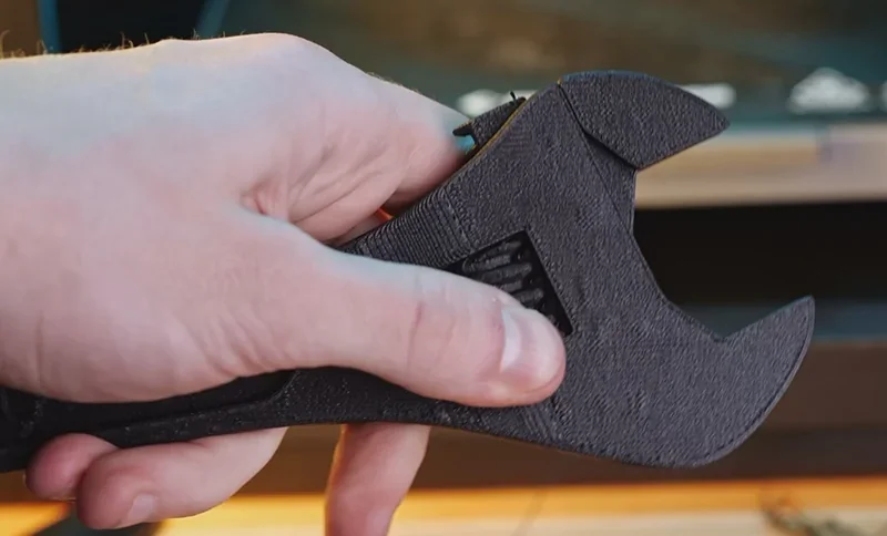 Hand holding a 3D-printed black wrench created by FlashForge Adventurer 5M Pro, showcasing precise details and craftsmanship.