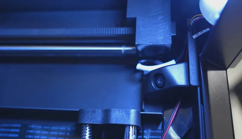 Flashforge Adventurer 5M Pro interior view, showing blue-lit printing mechanism and components, highlighting precision engineering.