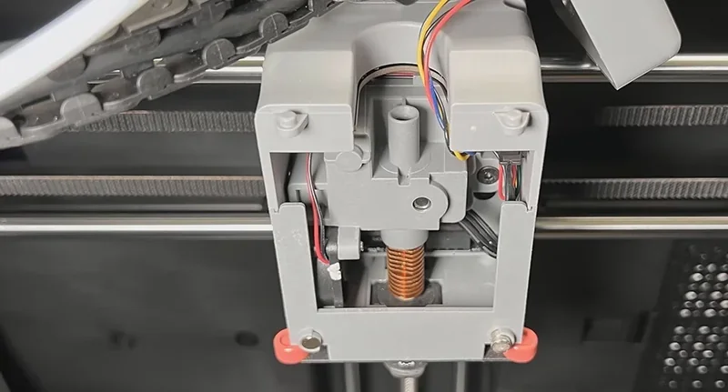 Flashforge Adventurer 5M Pro 3D printer's interior mechanics, featuring visible wiring, belts, and parts inside a black and gray casing, showcasing precision engineering.