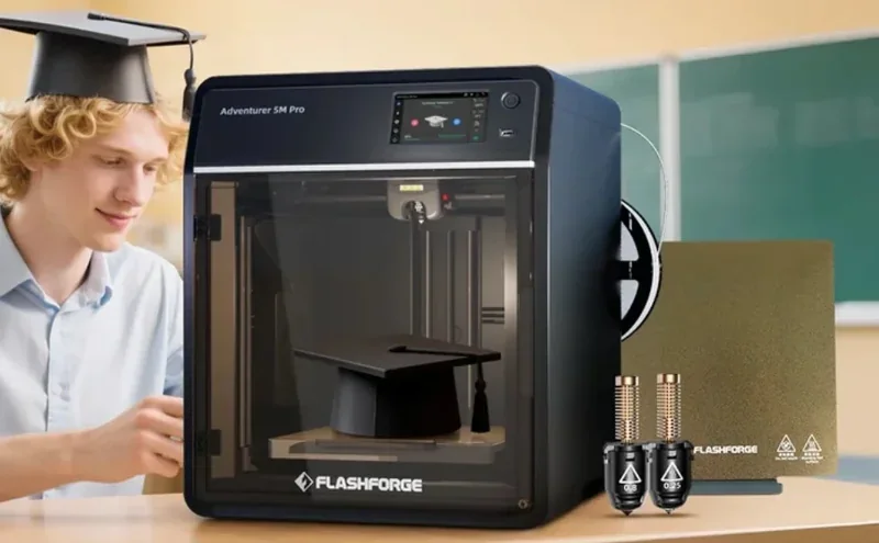 Flashforge Adventurer 5M Pro 3D printer with printed graduation cap, filament spools, and heated bed; young person in classroom setting wearing a cap.