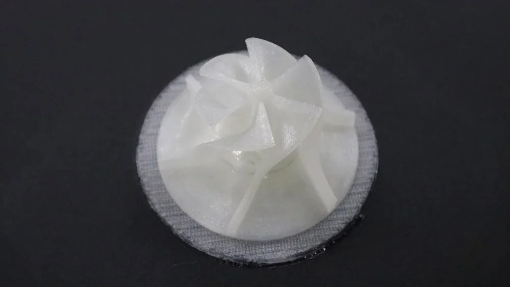 White 3D-printed turbine prototype created by Flashforge Creator 4, set on a dark surface showcasing intricate blade details.