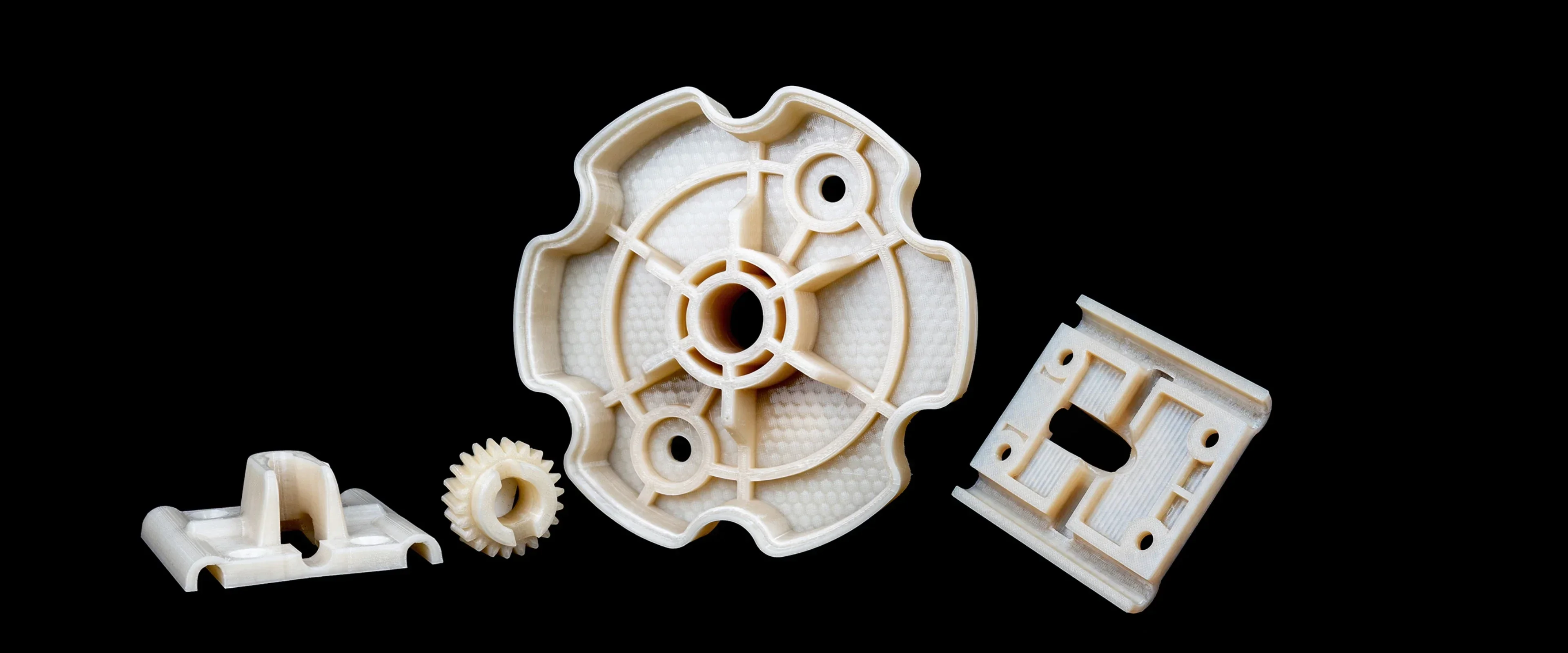 3D printed parts by Flashforge Creator 4; intricate designs of a gear, bracket, and panel, set against a black background.